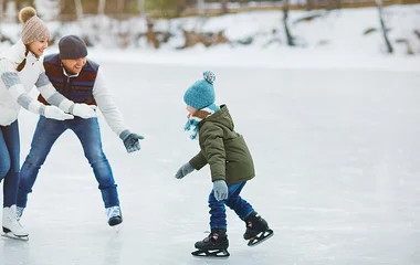 Pai, mãe e filho patinando no gelo.
