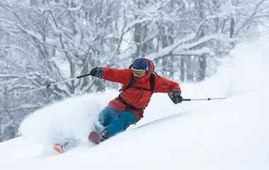 Homem esquiando e levantando a neve.
