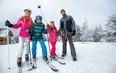 Família com roupas e equipamentos de esqui na neve.
