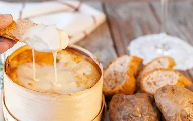 Pessoa passando uma torrada no queijo derretido.