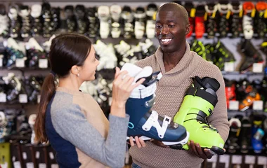 Mulher mostrando bota de esqui para o homem.