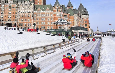 Pessoas descendo de trenó na neve.