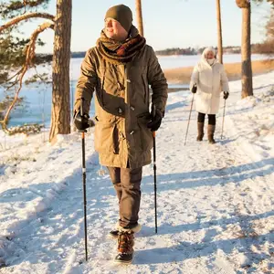 Homem caminhando na neve com uma mulher vindo na sequência.