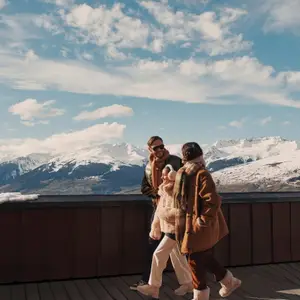 Família caminhando pelo resort, com montanhas cobertas de neve como pano de fundo