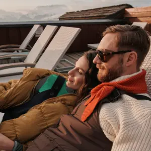 Casal deitado em cadeira, lendo um livro