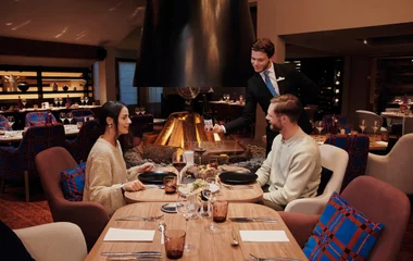 Casal em restaurante, enquanto garçom serve o vinho.
