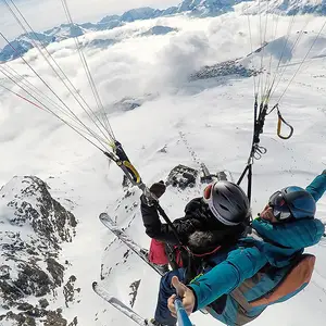Duas pessoas saltando de parapente nos alpes.
