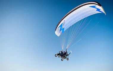 Duas pessoas no alto com um paramotor.