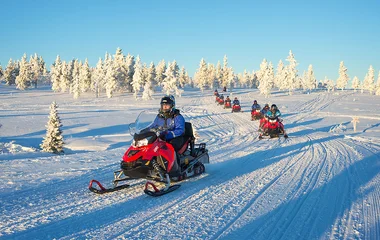 Grupo de pessoas andando de snowmobile.