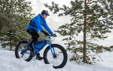 Homem de azul andando de mountain bike.