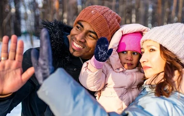Mãe, pai e filha usando roupas de neve.