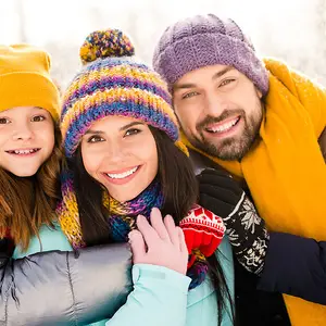 Mãe, pai e filha sorrindo em paisagem de neve.