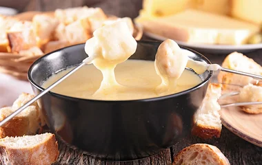 Fondue de queijo com acompanhamentos ao redor.