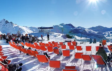 Cadeiras laranjas espalhadas sobre a neve para um evento musical.