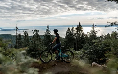 Mulher observando a paisagem de onde está parada com a bicicleta.