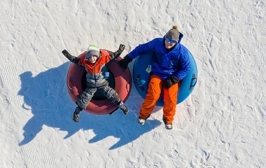 Homem e criança praticando snowtubing no Canadá.