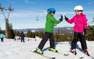 Crianças dando hi-five em estação de esqui.