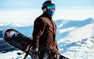 Homem segurando a prancha de snowboard.