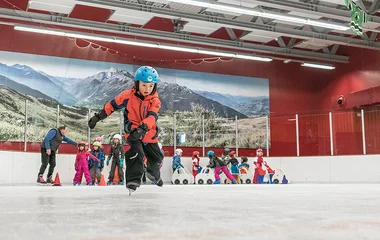 crianças em pista praticando patinação no gelo