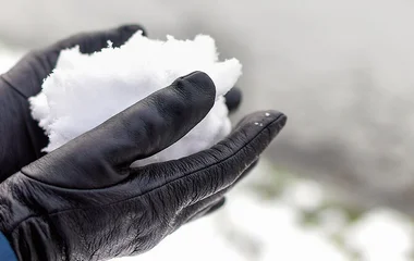 Pessoa usando luvas de couro preto enquanto segura a neve.