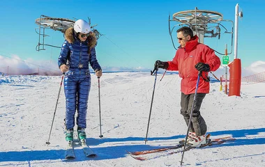 Duas pessoas com roupas e equipamentos de esqui.