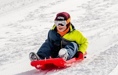 Criança em pista de toboga na neve