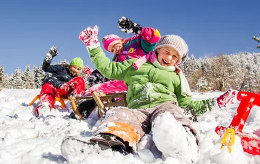 Três crianças se divertindo com o trenó de neve.