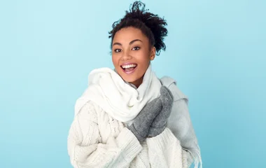 Mulher usando luvas cinzas e roupas de frio brancas.