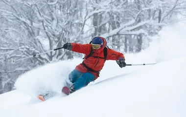 Pessoa esquiando com roupa vermelha e azul.