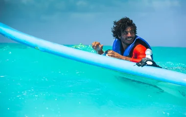 homem em mar azul com prancha de surf