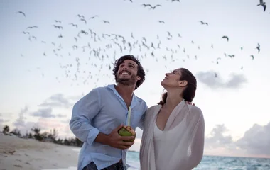 casal observando passáros voando em praia