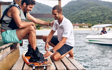 Instrutor ajudando homem a colocar a prancha de wakeboard.