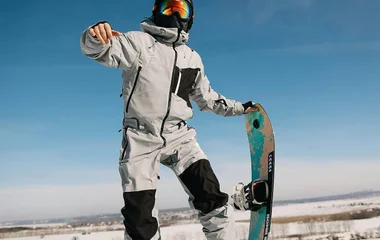 Homem saltando enquanto segura a prancha de snowboard.