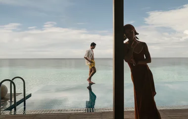 Homem e mulher numa piscina com borda infinita.