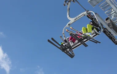 duas pessoas prontas para esquiar saindo de teleférico