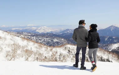 casal abraçados de costas apreciando o visual nevado