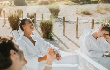 amigos sorrindo em praia vestindo roupão branco