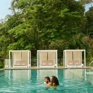Casal na piscina com vista para a natureza.