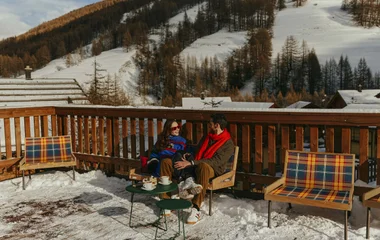 casal tomando café juntos em deque de madeira na neve