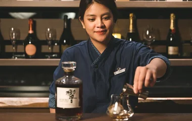 Mulher colocando bebida no copo, num dar do Club Med.