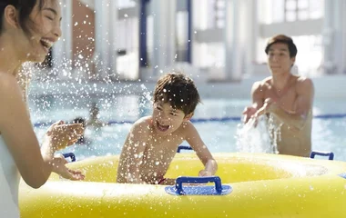 Pai, mãe e filho na piscina do resort.