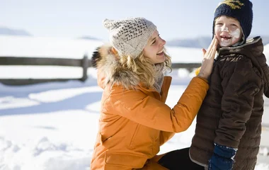 Mãe passando protetor no filho