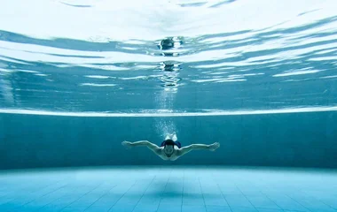 Homem nadando na piscina do resort.