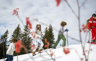Família caminhando com raquetes na neve.