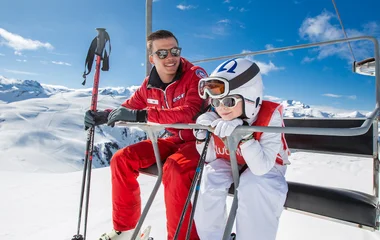 Kid with ski instructor on a ski lift