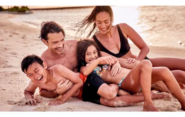 A man and a woman walking on a beach with palm trees