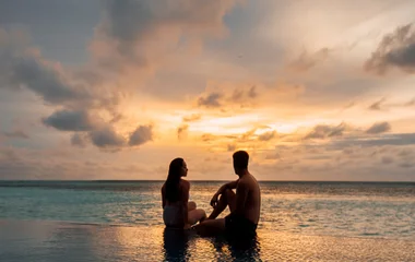 Couple in infinity pool during sunset