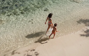 Kid with his mom walking on the beach