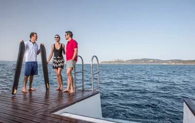 Dos huéspedes y un instructor en la cubierta del barco.