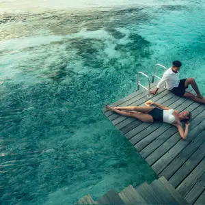 Casal no deck próximo ao mar azulado.